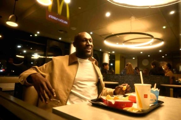 Image of Stormzy sitting in a McDonald's restaurant with a McDonald's meal.