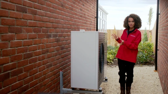 Woman standing by the side of a heat pump.
