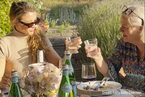 Two women enjoying an outdoor lunch with bottles of S.Pellegrino water on the table.